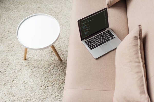 high angle view of programmer laptop with code on screen on cozy couch