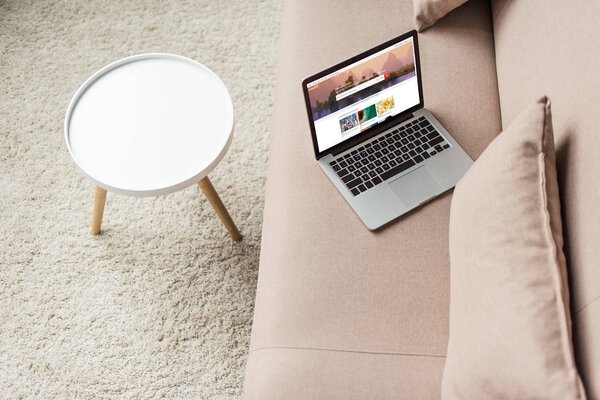 high angle view of laptop standing on cozy couch with shutterstock homepage website on screen