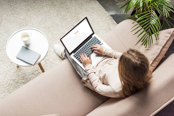 high angle view of woman at home sitting on couch and using laptop with google search on screen