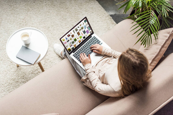 high angle view of woman at home sitting on couch and using laptop with pinterest on screen