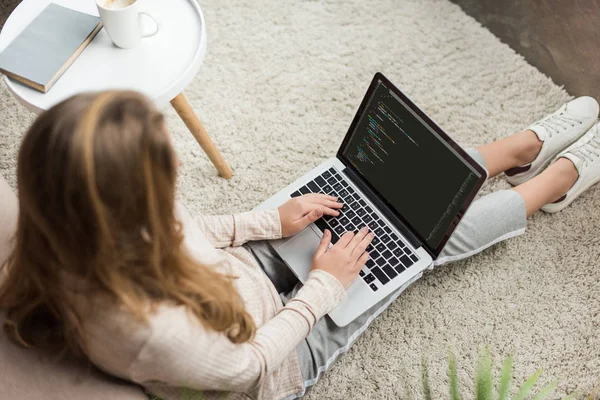 高角度视角的年轻女性开发者编码与笔记本电脑在家里 — 图库照片