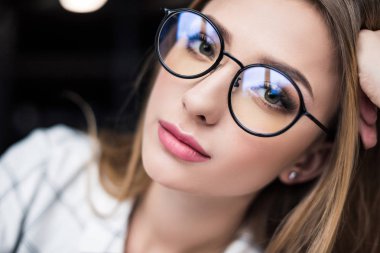 close-up portrait of beautiful young woman in eyeglasses looking at camera clipart