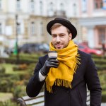 Handsome man in autumn outfit drinking coffee on bench