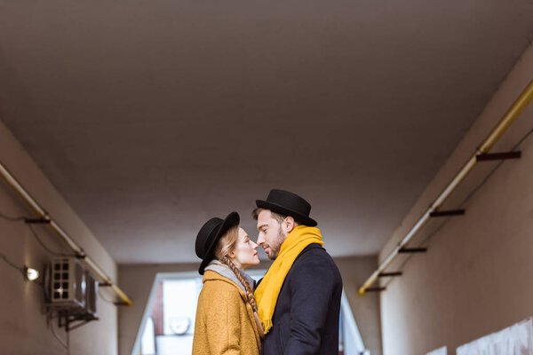 молодая нежная пара в осеннем наряде смотрит друг на друга
