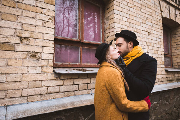 привлекательная молодая пара целуется рядом со зданием
