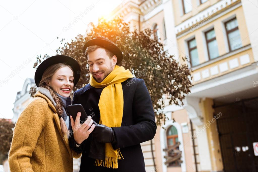 beautiful young couple in autumn outfit looking at smartphone