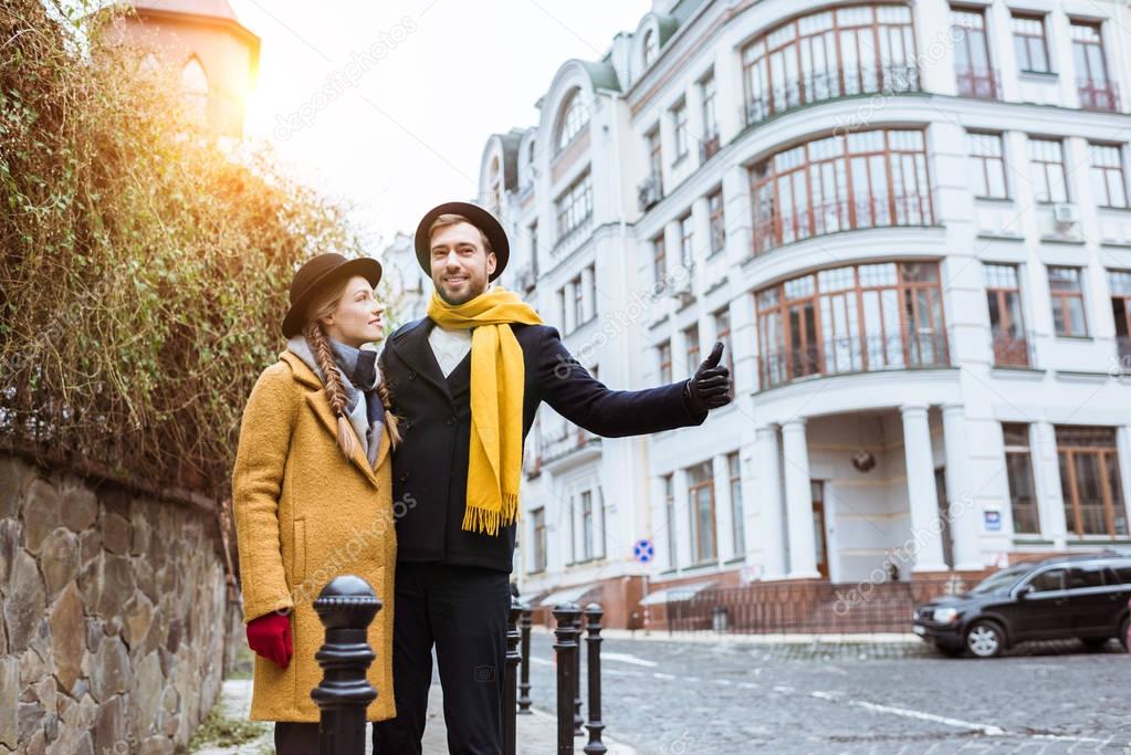 young beautiful couple catching taxi on city street