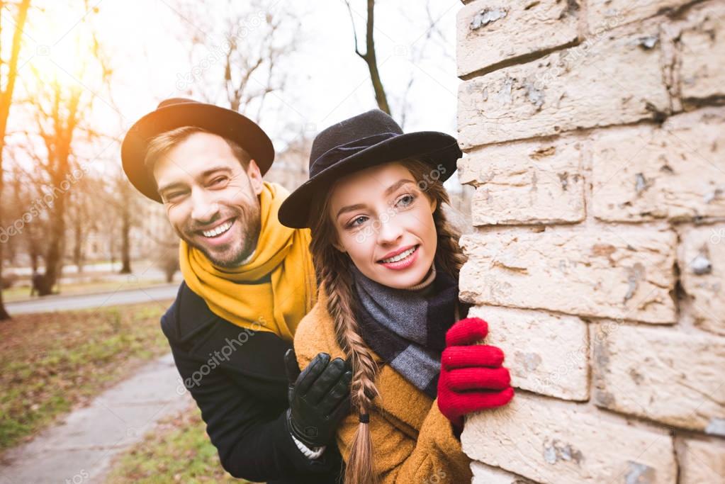 cheerful young couple in autumn outfit looking at corner