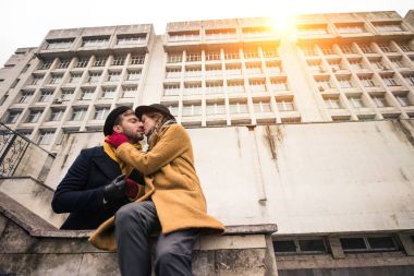 cheerful attractive young couple hugging infront of building clipart