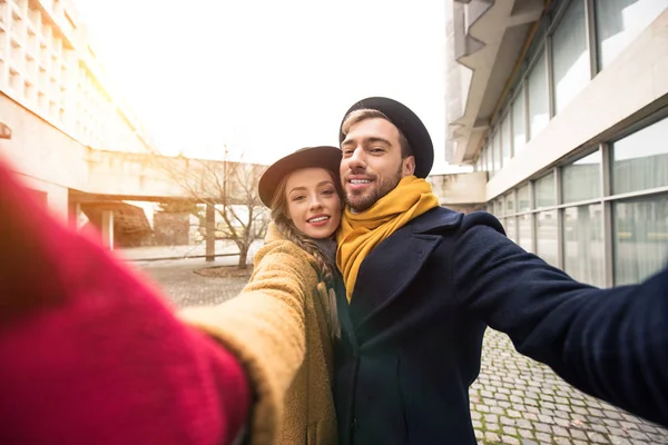 happy hugging young couple taking selfie infront of building