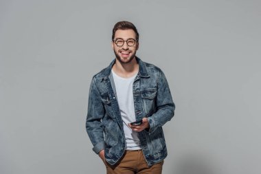 akıllı telefon tutarak ve gri izole kamera gülümseyen neşeli genç adam