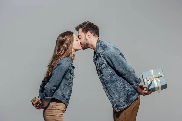 Gyönyörű Fiatal Pár Szerelem Ajándék Dobozok Csók Elszigetelt Szürke Gazdaság — Stock Fotó