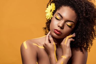 Şehvetli Afro-Amerikan olan kadın sanatsal makyaj ve saç üzerinde turuncu arka plan izole hayal gerbera