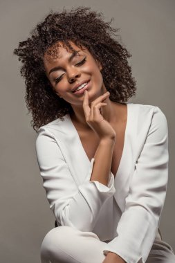 Gri arka plan üzerinde izole dudaklarında parmak ile Beyaz gömlekli şehvetli genç Afro-Amerikan kadın