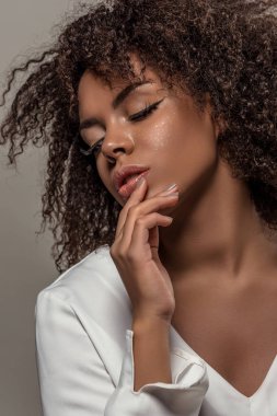 Beyaz gömlek gri arka plan üzerinde izole şehvetli genç Afro-Amerikan kadın