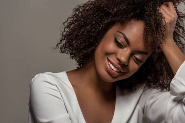 Gri arka plan üzerinde izole el Beyaz gömlekli şehvetli genç Afro-Amerikan kadın dayanıyor
