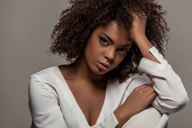 Gri arka plan üzerinde izole el genç ihale Afrikalı-Amerikalı kadın Beyaz gömlekli dayanmaktadır