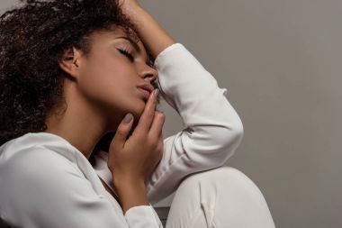 Beyaz gömlek gri arka plan üzerinde izole dudaklarına dokunmadan genç ihale Afrikalı-Amerikalı kadın
