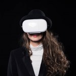Beautiful brunette woman using virtual reality headset isolated on black
