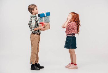 sevimli küçük kız gözler gri izole kapatmak için hediyeler sunan çocuk yan görünüm