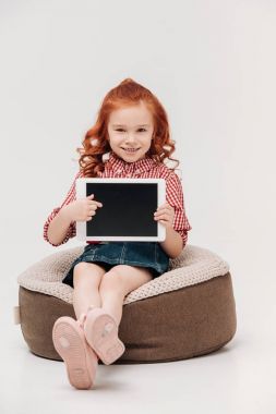 kameraya gülümseyen ve dijital tablet vasıl boş ekran gri izole ile işaret eden çok güzel kızıl saçlı çocuk