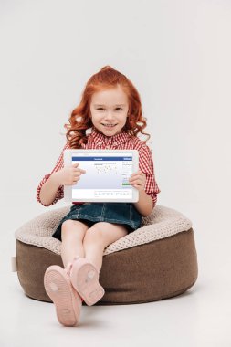 ekranda gri izole dijital tablet facebook web sitesi ile tutarak kameraya gülümseyen sevimli küçük kız