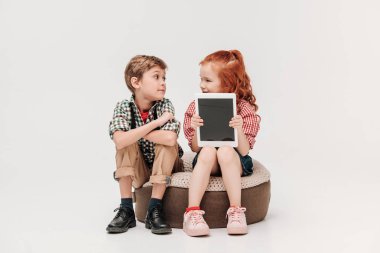 güzel çocuklar birbirine bakarak ve boş ekran gri izole ile dijital tablet gösteren