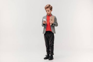 smartphone ve gri izole kitap ile şık küçük öğrenci