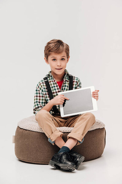 cute little boy showing digital tablet with blank screen and looking at camera isolated on grey