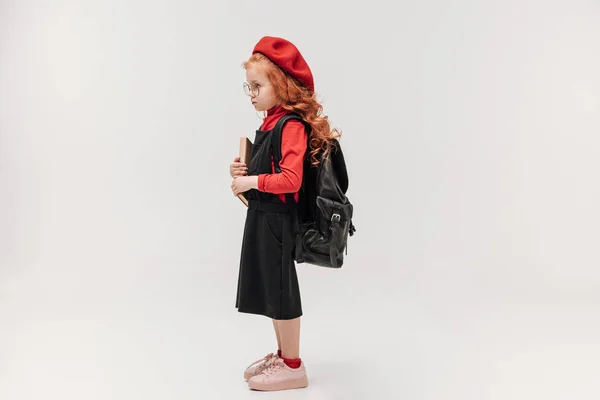 愛らしい小さな女子高生本とバックパック グレーで隔離赤いベレー帽の側面図 — ストック写真