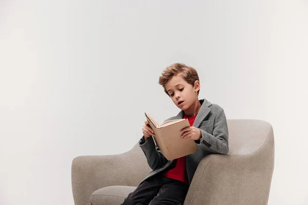 Focused Little Schoolboy Reading Book Armchair Isolated Grey — Stock Photo, Image