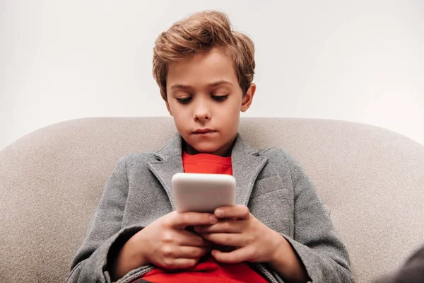 Ernstige Jongetje Met Smartphone Zittend Fauteuil Geïsoleerd Grijs — Stockfoto