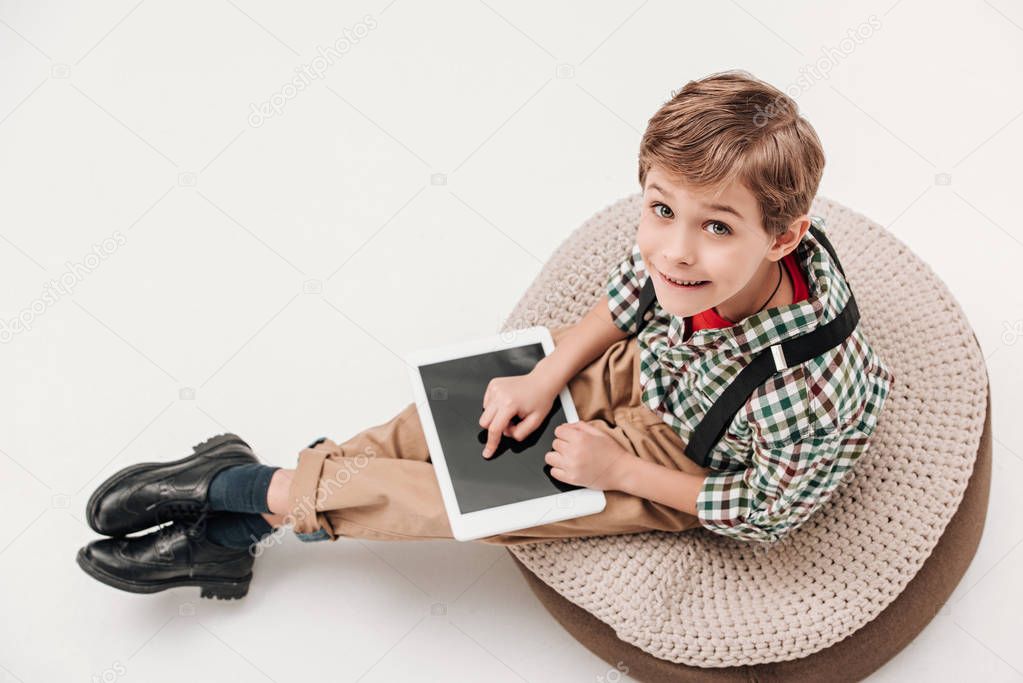 high angle view of little boy using digital tablet and looking at camera isolated on grey