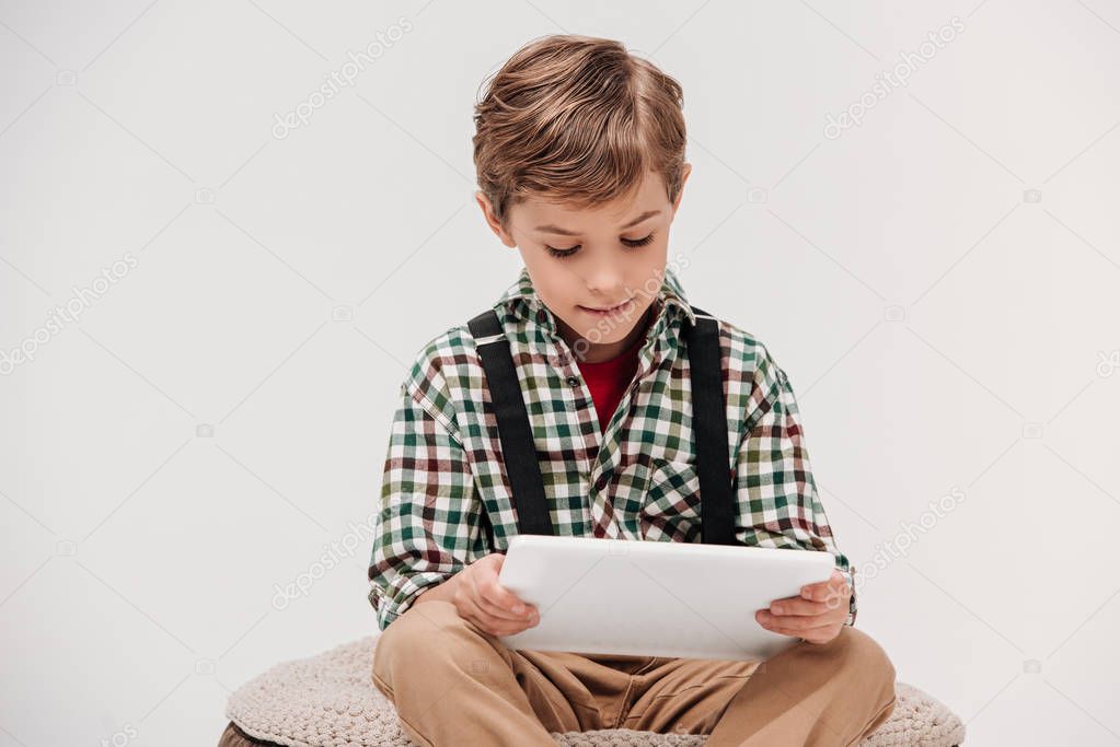 cute smiling little boy using digital tablet isolated on grey