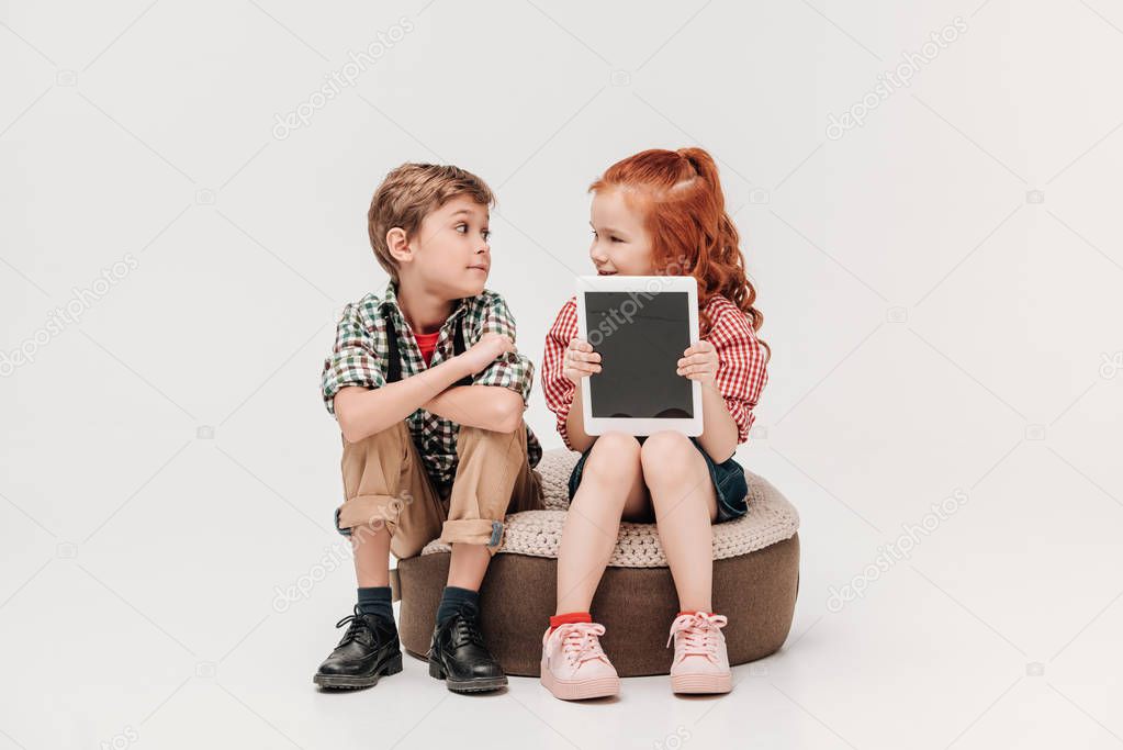 beautiful kids looking at each other and showing digital tablet with blank screen isolated on grey
