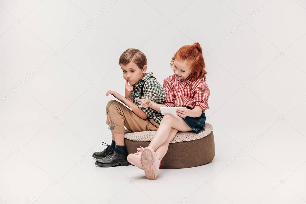 adorable little kids using smartphone and digital tablet isolated on grey