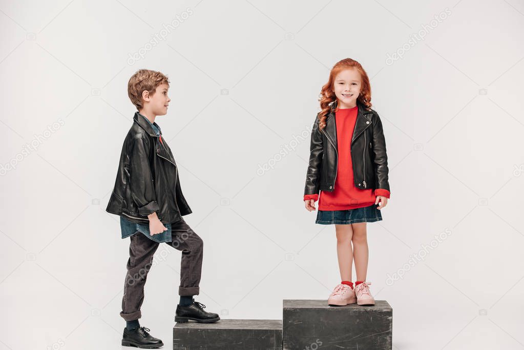 adorable little kids couple on stairs isolated on grey
