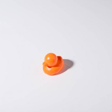 close-up view of one orange rubber duck isolated on grey clipart