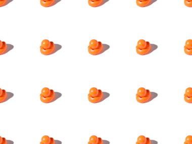 seamless pattern of small orange rubber ducks toys on white clipart