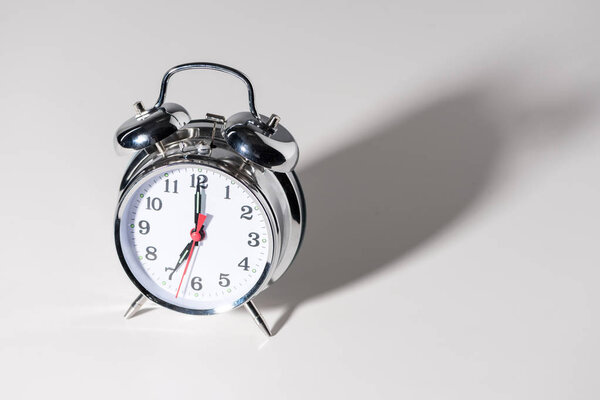 close-up view of shiny alarm clock with shadow on grey