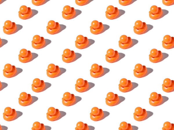 seamless pattern of small orange rubber ducks on white 