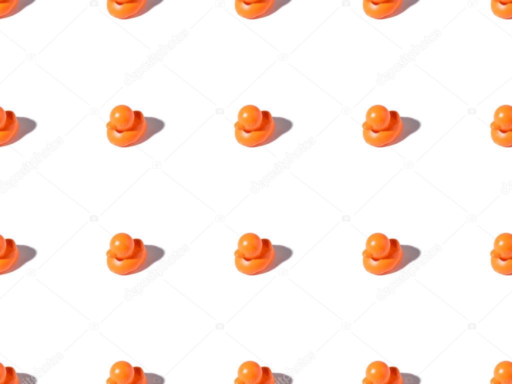 seamless pattern of small orange rubber ducks toys on white