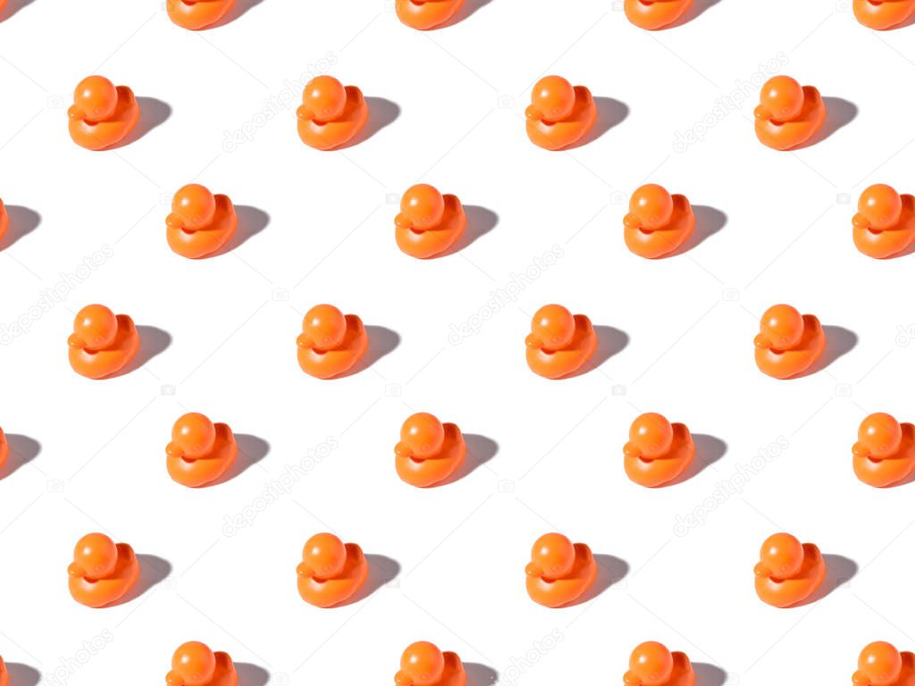 seamless pattern of cute orange rubber ducks with shadows on white 