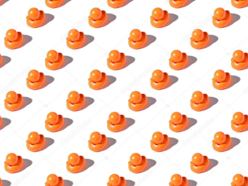 seamless pattern of small orange rubber ducks on white 