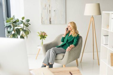 Orta yaşlı işkadını smartphone ofiste tarafından konuşmak yüksek açılı görünüş