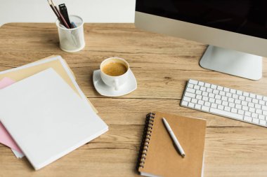 fincan kahve, ofis malzemeleri ve işyerinde masaüstü bilgisayar görmek