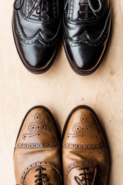top view of black and brown pairs of leather shoes on wooden floor  clipart