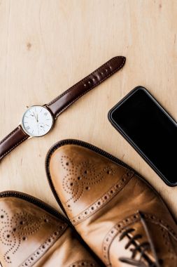 top view of watch, smartphone and shoes on wooden table clipart
