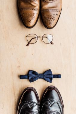 top view of shoes, glasses and tie bow on wooden surface clipart