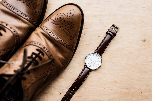 木质表面的棕色鞋和手表的顶部视图 — 图库照片